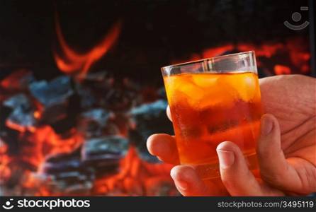 glass of drink in his hand a background of fire