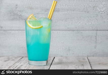 Glass of electric lemonade cocktail garnished with lemon