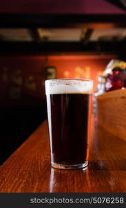 Glass of fresh beer on counter in pub. Glass of fresh beer on pub table