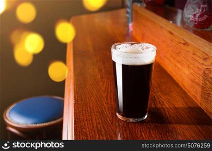 Glass of fresh beer on counter in pub. Glass of fresh beer on pub table
