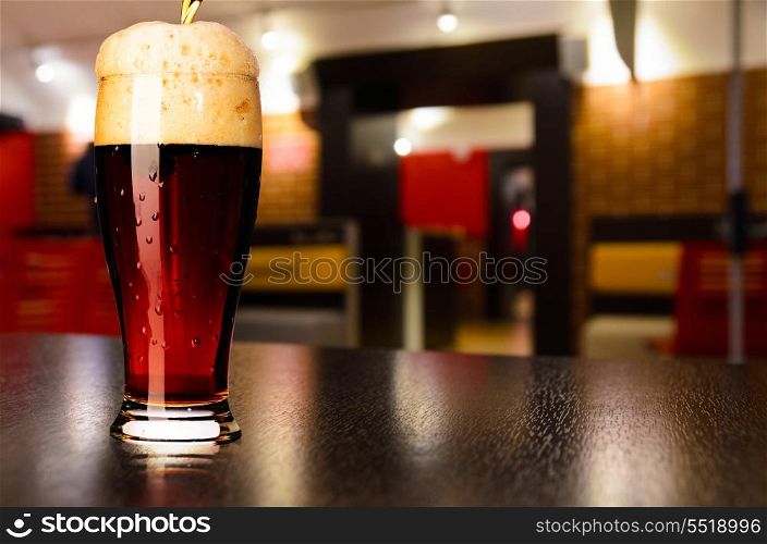 glass of fresh draft dark beer on table in pub. draft beer