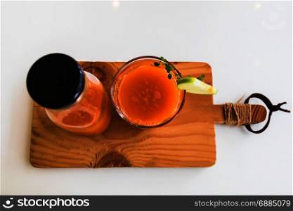 Glass of fresh juice with sliced green apple on wooden board