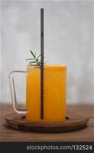 Glass of fresh orange juice with slice on wooden table