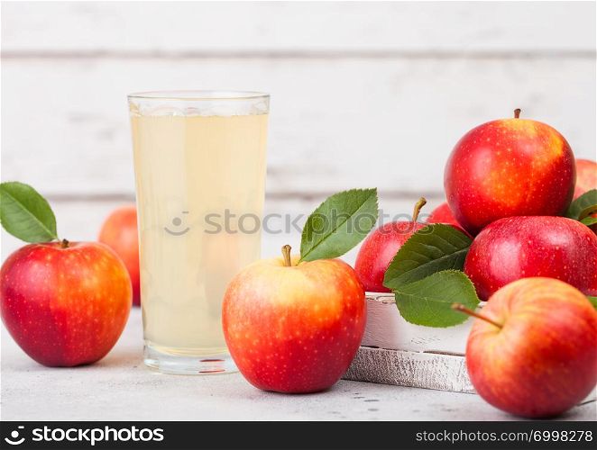 Glass of fresh organic apple juice red apples in box on wooden background Space for text