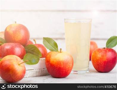 Glass of fresh organic apple juice with braeburn pink lady apples in box on wooden background. Space for text