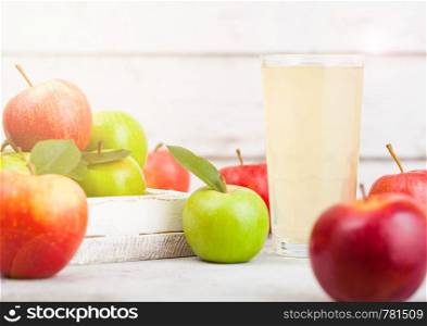 Glass of fresh organic apple juice with braeburn pink lady apples in box on wooden background. Space for text