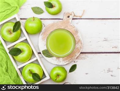 Glass of fresh organic apple juice with granny smith green apples in box on wood background.
