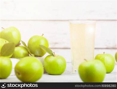 Glass of fresh organic apple juice with green apples in box on wooden background with sun light. Space for text
