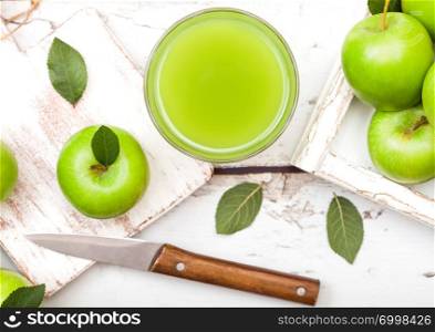 Glass of fresh organic apple juice with green apples in box on wood background.
