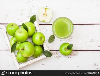 Glass of fresh organic apple juice with green apples in box on wood background.