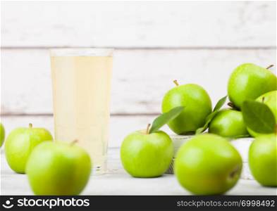 Glass of fresh organic apple juice with healthy green apples in box on wooden background. Space for text