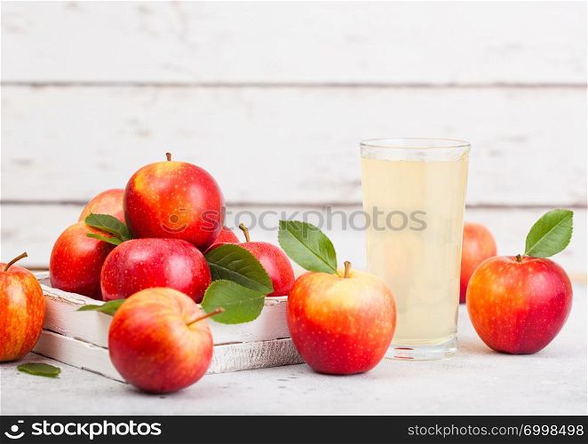 Glass of fresh organic apple juice with healthy red apples in box on wooden background Space for text