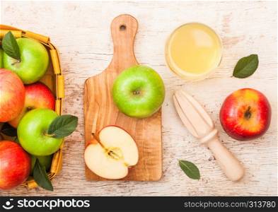 Glass of fresh organic apple juice with pink lady red and granny smith green apples in vintage basket on wood background .