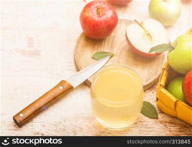 Glass of fresh organic apple juice with pink lady red and granny smith green apples on chopping board on wooden background .