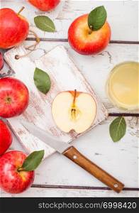 Glass of fresh organic apple juice with pink lady red apples on chopping board on wooden background.