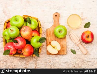 Glass of fresh organic apple juice with red and green apples in vintage basket on wood background