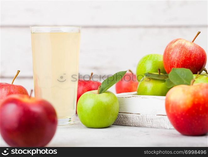 Glass of fresh organic apple juice with red and green apples in box on wooden background. Space for text