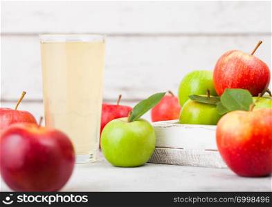 Glass of fresh organic apple juice with red and green apples in box on wooden background. Space for text