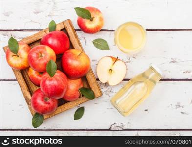 Glass of fresh organic apple juice with red apples in vintage box on wood background.