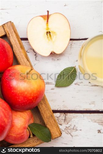 Glass of fresh organic apple juice with red apples in vintage box on wood background