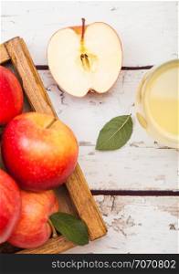 Glass of fresh organic apple juice with red apples in vintage box on wood background