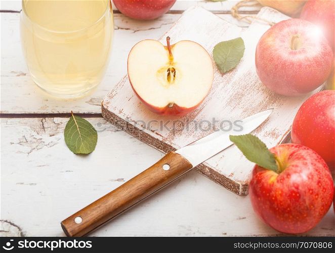 Glass of fresh organic apple juice with red apples on chopping board on wooden background.