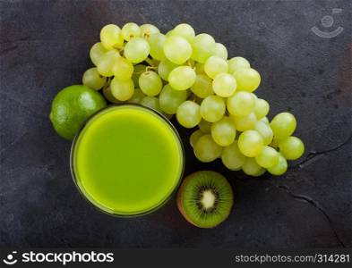 Glass of fresh smoothie organic green toned fruits on stone kitchen background. Grapes with kiwi and lime.