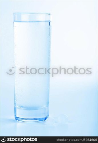 Glass of fresh water with medical pills, studio isolated, health care concept