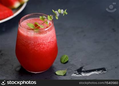 Glass of healthy watermelon smoothie with mint leaves on dark background