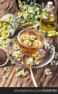 glass of herb tea with chamomile. mug of herbal tea with chamomile flowers on rustic wooden table