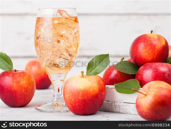 Glass of homemade organic apple cider with fresh apples in box on wooden background, Glass with ice cubes