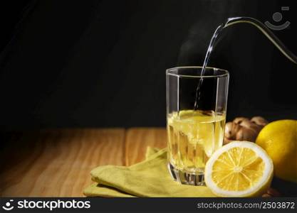 Glass of Hot Infusion Ginger lemon drink. Organic and Healthy Lifestyle. Fresh Water with lemon Sliced. present on Table with Natural light by the Window. Seasonal Beverage.