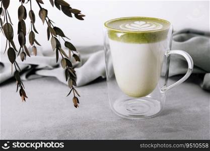Glass of hot matcha green tea latte with tulip pattern