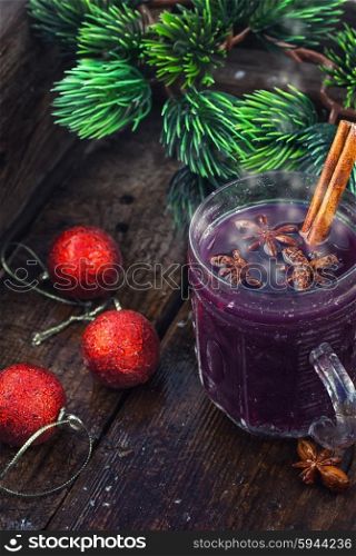 glass of hot wine. glass of wine with the cinnamon stick and star anise amid the branches of the spruce.