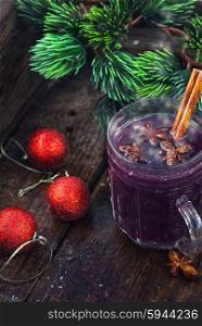 glass of hot wine. glass of wine with the cinnamon stick and star anise amid the branches of the spruce.