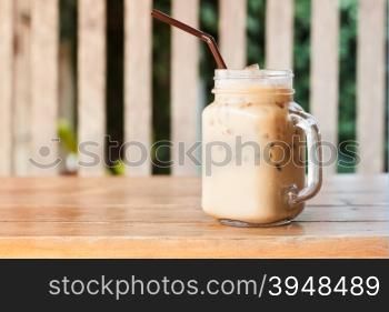 Glass of iced coffee on wooden table with vintage filter style, stock photo