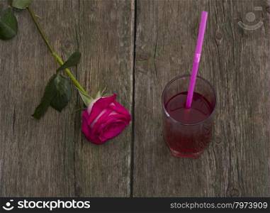 glass of juice and lonely red rose on a table