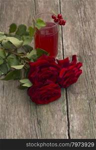 glass of juice, currant on a glass and a bouquet of red roses