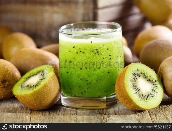 glass of kiwi juice with fresh fruits on wooden table