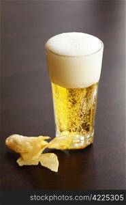 glass of light beer and chips on a wooden table