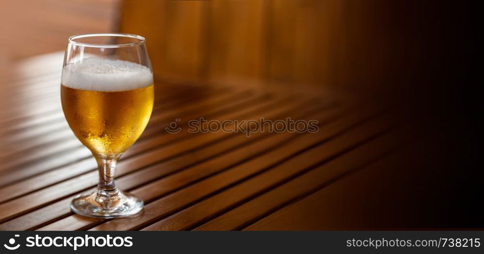 Glass of light beer on the wooden table, with copy space