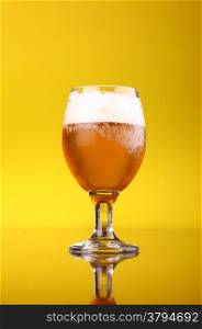 Glass of light beer over a bright yellow background