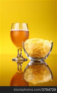 Glass of light beer with snacks over a bright yellow background