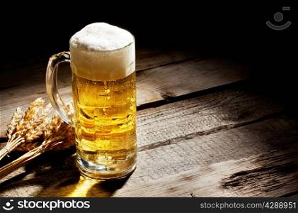 Glass of light beer with spikelets on wooden table