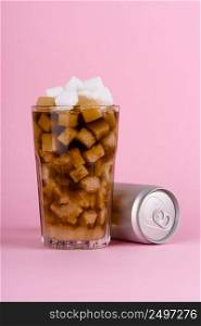 Glass of lump sugar cubes and soft cola drink with aluminum can on pink pastel background. Unhealthly diet with sweet sugary soft drinks concept.