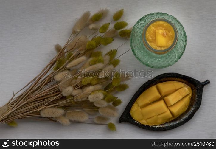 Glass of Mango shake with Fresh ripe yellow mango fruit. Fresh tropical fruit smoothies on white background. Healthy detox herbal drink, Fruit on the summer season, Top view Space for text, Selective focus.
