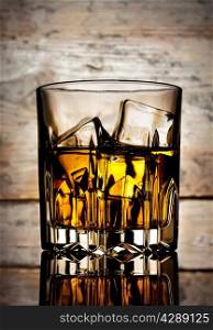 Glass of mellow whiskey on a wooden background