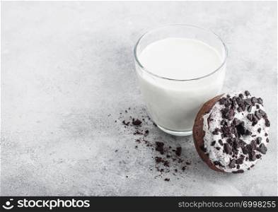 Glass of milk and doughnut with black cookies on stone kitchen table background.