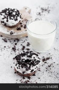 Glass of milk and doughnuts with black cookies on stone kitchen table background.