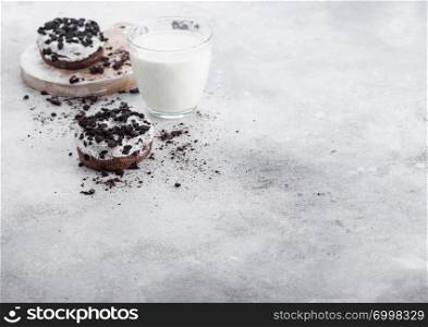 Glass of milk and doughnuts with black cookies on stone kitchen table background.